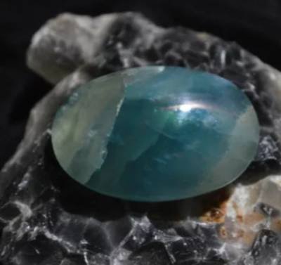 Polished blue onyx gemstone on a natural rock matrix, showcasing healing crystal properties.